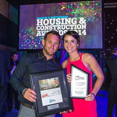 A man and woman holding awards at the Mackay & Whitsunday Housing & Constructions Awards 2014